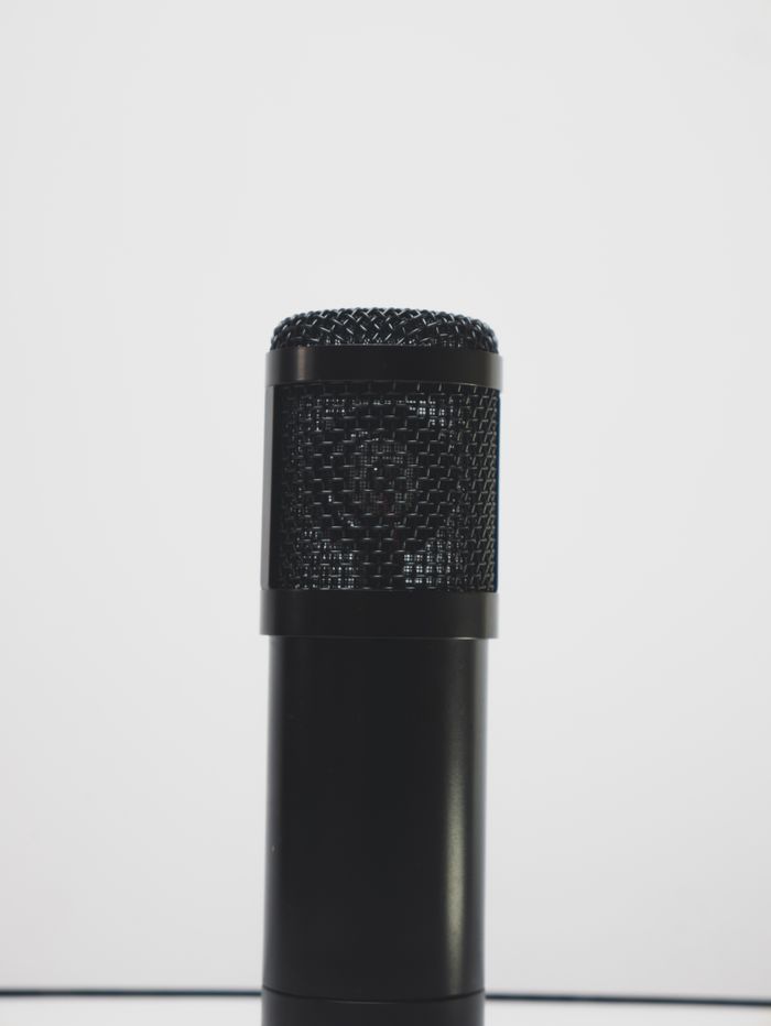 Gros plan d’un microphone noir sur fond blanc, idéal pour des thèmes liés à l’enregistrement audio.